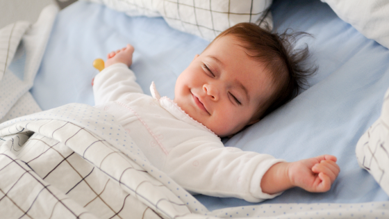baby ligt glimlachend te slapen in bed