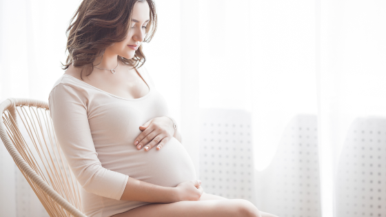 Zwangere vrouw zit voor het raam in een schommelstoel