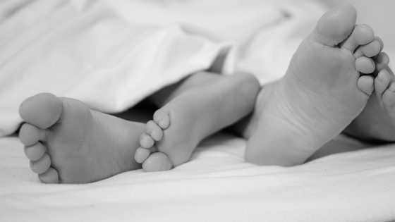 twee paar voeten die onder de deken vandaan komen