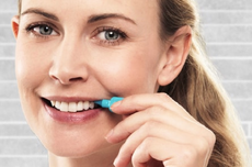 vrouw met een interdentale reiniger tussen haar tanden