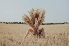 vrouw zit met benen wijd in een korenveld