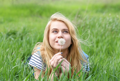 vrouw liggend in gras met paardebloem