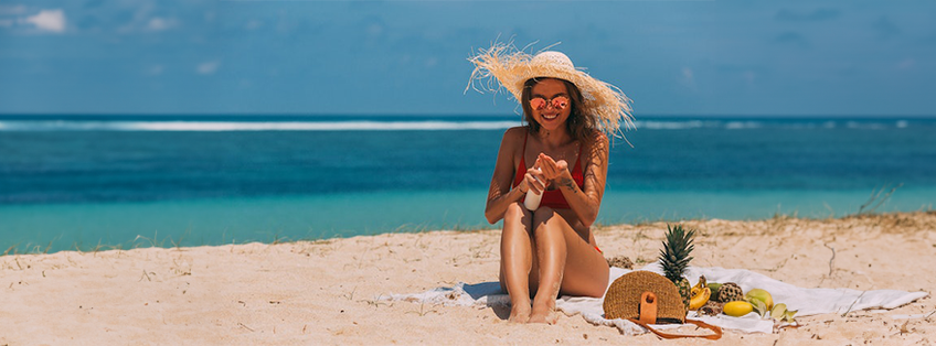 vrouw op strand die zich insmeert met zonnebrand