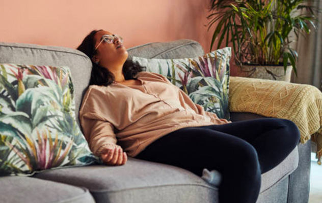 vrouw zit futloos op de bank zonder energie