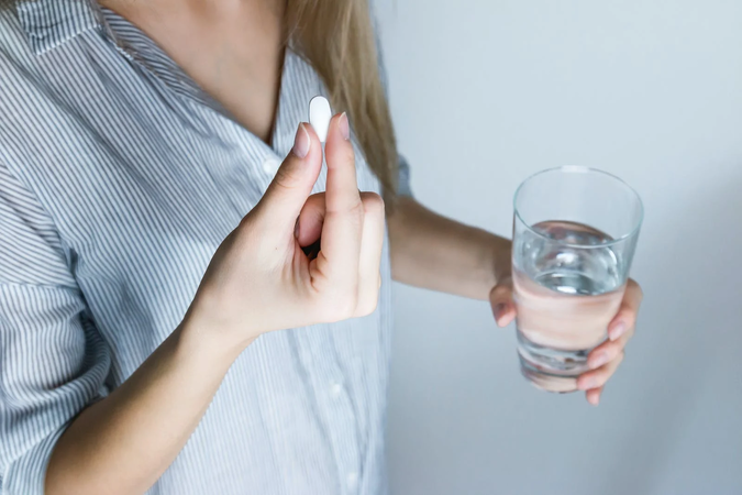 vrouw met tablet diclofenac en glas water