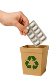 Een hand met een gebruikte pilstrip die in een kartonnen prullenbakje wordt gedaan waar een groen recycle icoon op staat