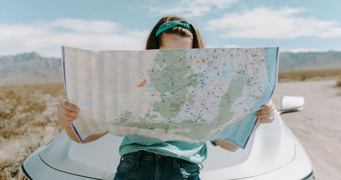 Vrouw onderweg naar vakantiebestemming kijkt op landkaart Vrouw onderweg naar vakantiebestemming kijkt op landkaart