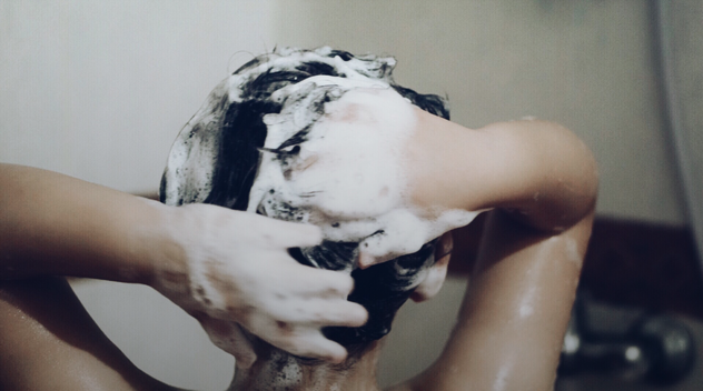 persoon aan het douchen shampoo in haar