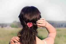 vrouw staat in veld met rug naar camera toe