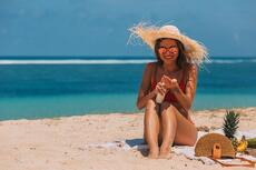 vrouw op strand die zich insmeert met zonnebrand