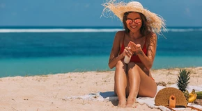 vrouw op strand die zich insmeert met zonnebrand
