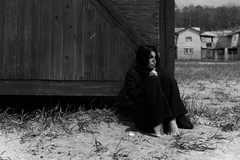 vrouw zit naast een schuur in zwarte kleding