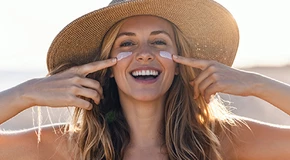 Vrouw smeert zonnebrand op wangen Vrouw smeert zonnebrand op wangen