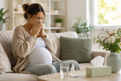 Zwanger en hooikoorts: vrouw met allergische klachten zoals niezen en verstopte neus op de bank thuis